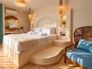 Une chambre à coucher moderne avec un grand lit, une banquette intégrée, un fauteuil en osier et des luminaires fixés au mur.
