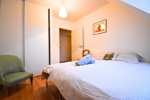 A bedroom with a bed, a chair, and a door leading to another room. - Senlis - Éclat d'Époque (Senlis)