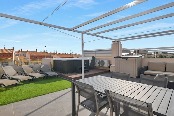 Une terrasse sur le toit avec des sièges extérieurs, un jacuzzi et un espace barbecue.