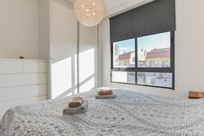 Une chambre à coucher avec un lit, une fenêtre donnant sur un beau paysage et un luminaire suspendu.