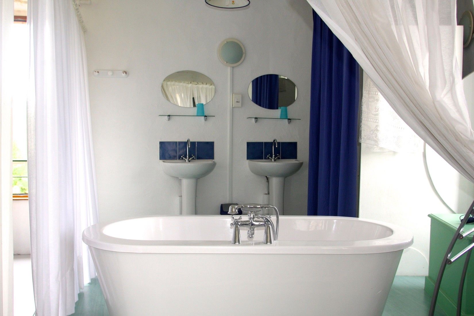 Une salle de bain avec une baignoire sur pieds, deux vasques fixées au mur et un miroir au-dessus de chaque vasque.