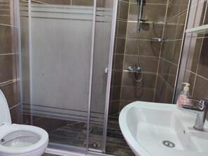 A bathroom with a glass-enclosed shower, a toilet, and a sink with a soap dispenser. - HOTEL YAMUR (ANAMUR)
