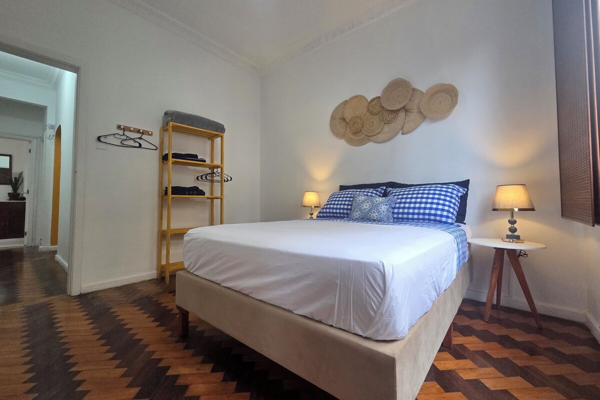 Une chambre à coucher avec un lit, des tables de chevet, une étagère fixée au mur et un plancher à motifs.