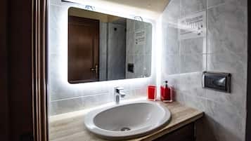 A modern bathroom with a marble sink, a mirror, and a hand dryer.