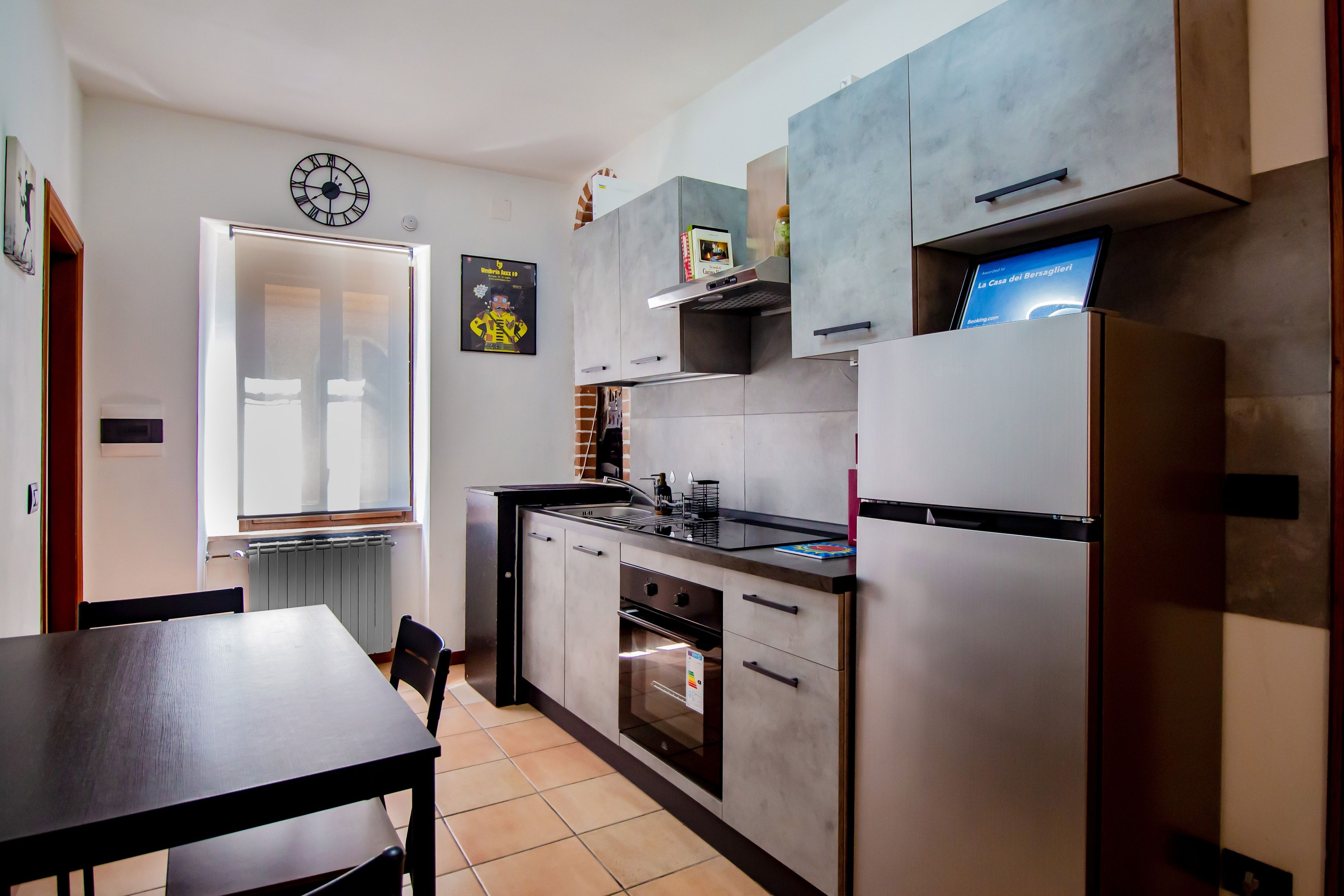 A modern kitchen with a built-in oven, a refrigerator, and a dining area with a table and chairs.
