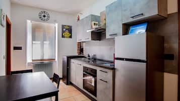 A modern kitchen with a built-in oven, a refrigerator, and a dining area with a table and chairs.