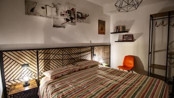 A bedroom with a bed, a chair, a nightstand, a geometric-patterned headboard, and wall art.