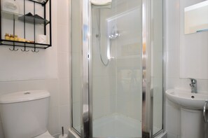 Un baño moderno con ducha envuelta en vidrio, inodoro y lavamanos.