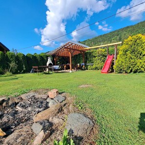 Offene Feuerstelle und Außensitzplatz unter der Pergola am Kamin.