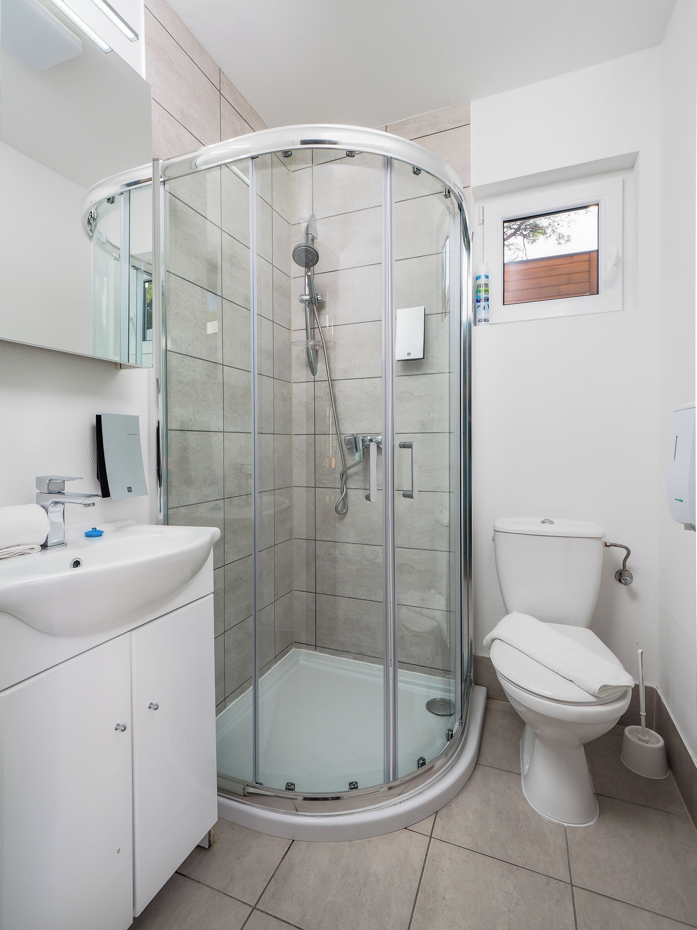 Un baño moderno con ducha envuelta en vidrio, un lavabo blanco y un inodoro.