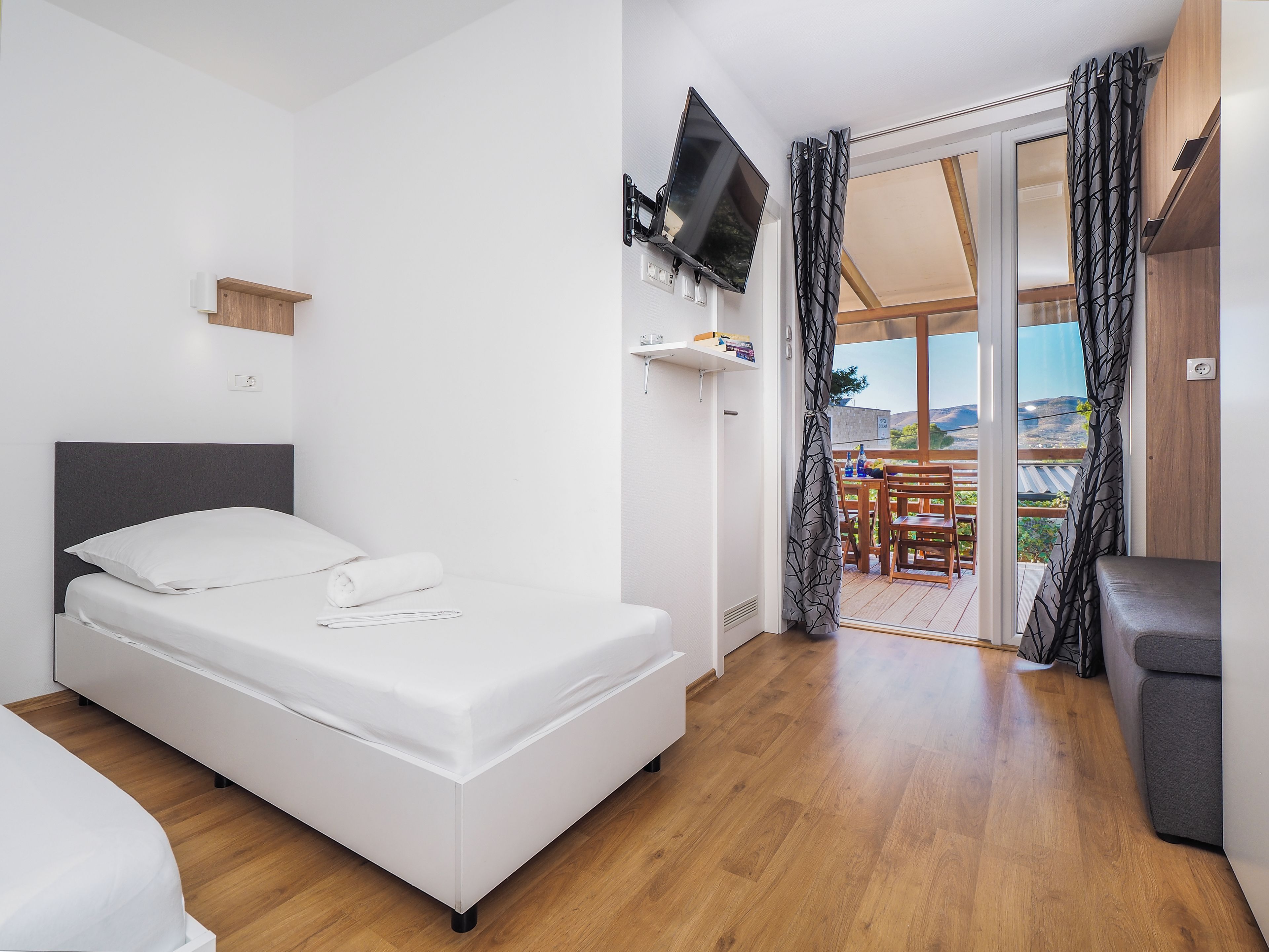 Un dormitorio moderno con cama, televisor y balcón con mesa y sillas.