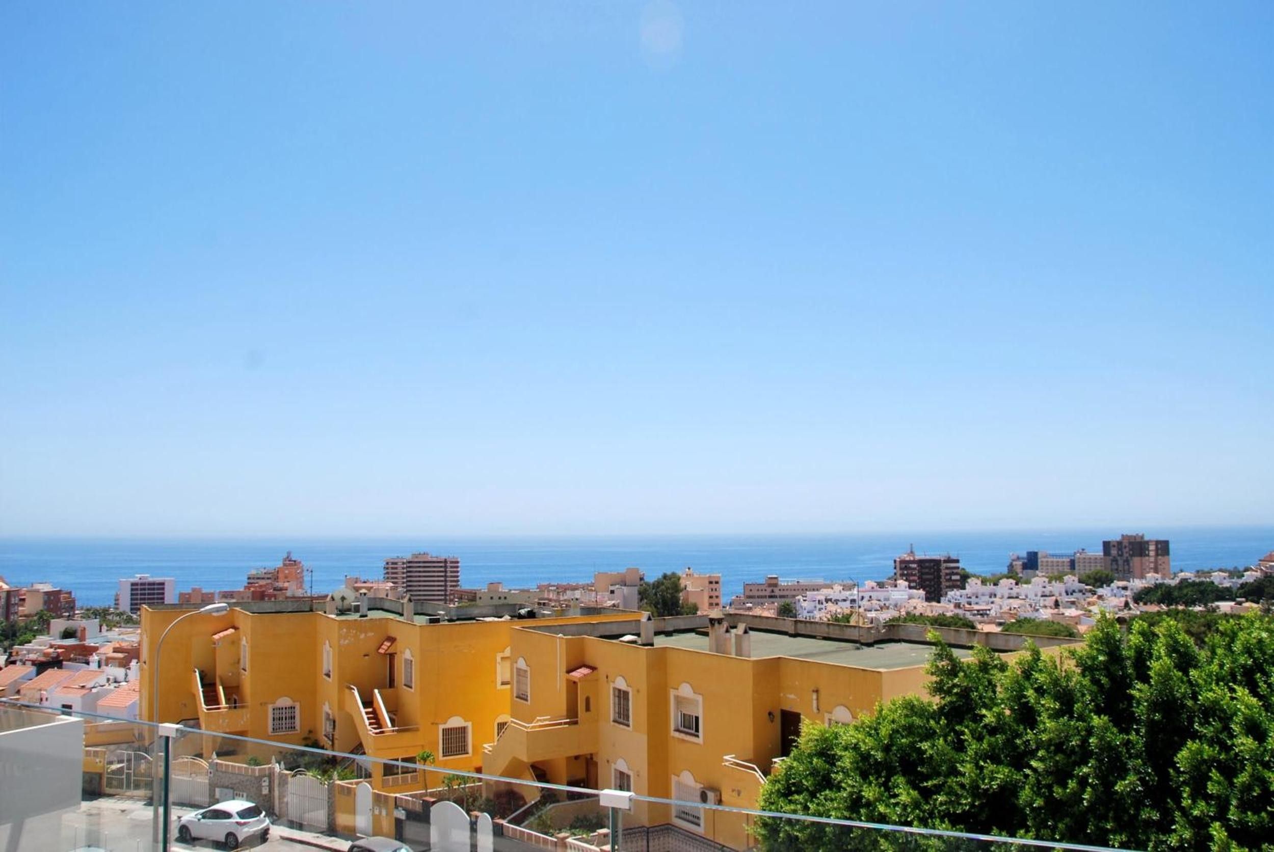 A coastal cityscape with yellow buildings and a clear view of the sea.