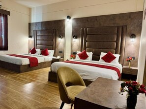 Ein Hotelzimmer mit zwei Betten, einem Esstisch und einem Stuhl.