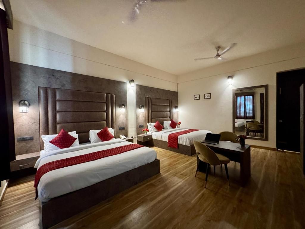A hotel room with two beds, a desk, and a chair.