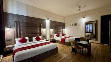 A hotel room with two beds, a desk, and a chair.