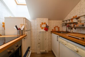 Een functionele keuken met een inbouwoven, vaatwasser en een radiator.
