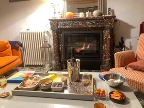 Un salon avec une cheminée, un radiateur et une table dressée avec de la nourriture et des boissons.