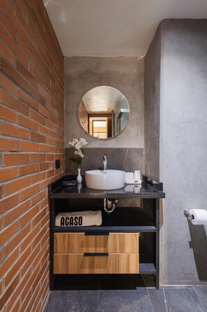 A bathroom with a round mirror, a white sink, a towel rack, and a vanity with a wooden drawer. - Apartment with Beautiful Views | 202 (Puebla)