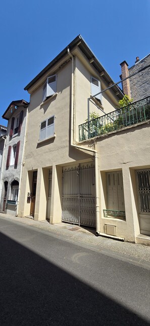 Un bâtiment à deux étages, doté d’un toit plat, d’un balcon orné de rampes en métal décoratives et d’une entrée fermée par un portail.