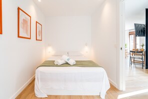 Una habitación de hotel con una cama, dos obras de arte enmarcadas en la pared, una colcha verde y vistas al comedor.