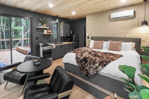 A modern bedroom with a large bed, a desk, and a dining table. - La P'tite Maison - On the Richibucto River (Weldford)