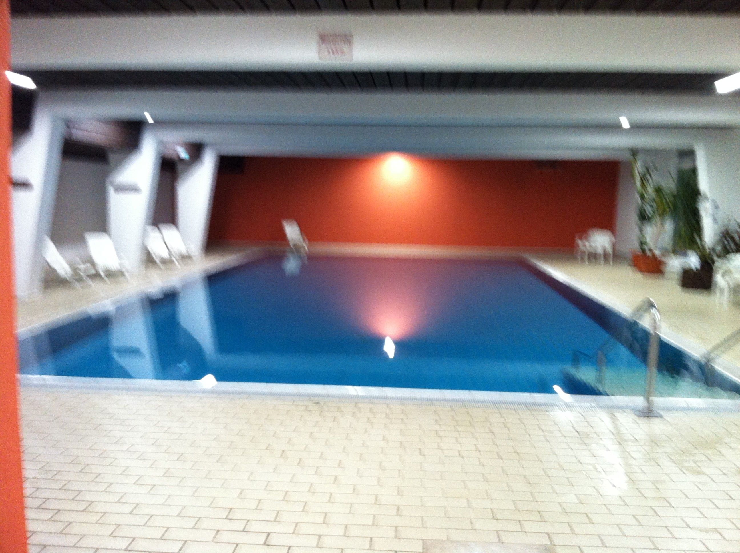 Ein Hallenbad mit gefliestem Boden und einer roten Wand im Hintergrund.
