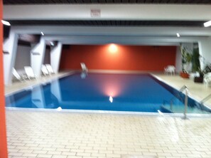 Ein Hallenbad mit gefliestem Boden und einer roten Wand im Hintergrund.