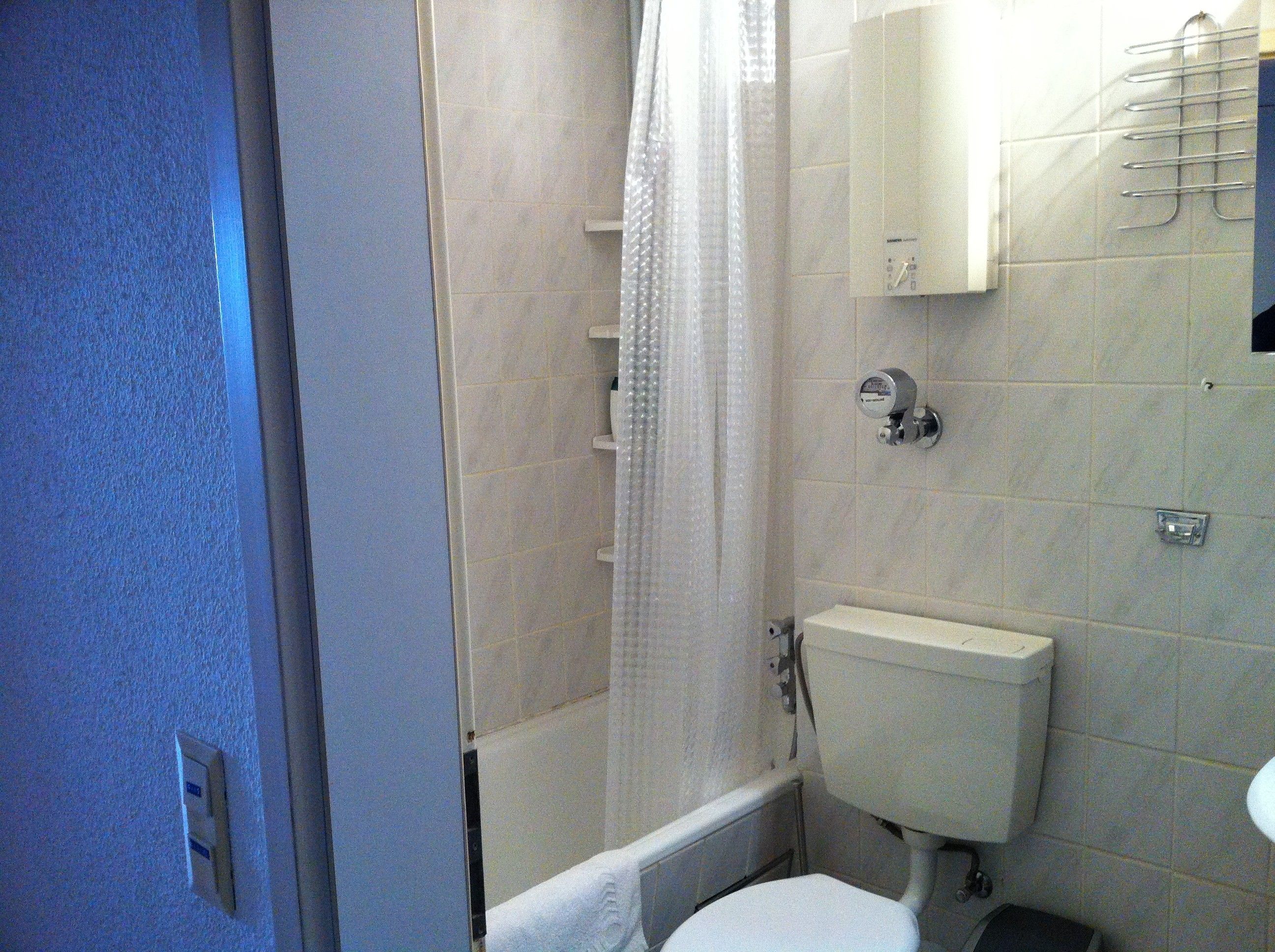 Ein Badezimmer mit Toilette, einer Duschkabine und einem Handtuchhalter.