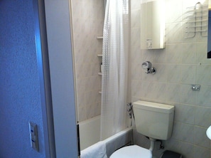 Ein Badezimmer mit Toilette, einer Duschkabine und einem Handtuchhalter.