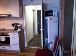 Eine kompakte Küche mit Mikrowelle, Kaffeemaschine und Kühlschrank.