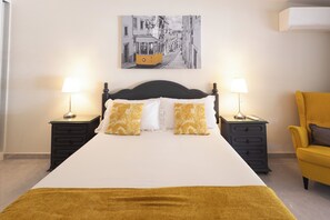 A hotel room with a bed, two bedside tables, a chair, and a wall-mounted artwork. - Quinta Aida Farmhouse Rooms (Lagoa)