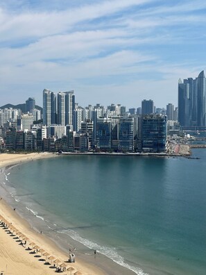 Un paysage urbain côtier avec de hauts immeubles, une plage de sable et une mer calme.