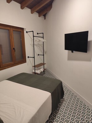 A bedroom with a bed, a window, a wall-mounted TV, and a clothes drying rack. - New Listing (Campo de Criptana)