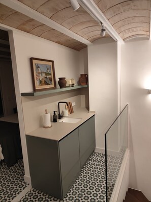 A bathroom with a modern sink, a mirror, and a shelf with decorative items. - New Listing (Campo de Criptana)