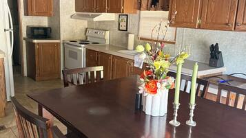 Una cocina con armarios de madera, una estufa blanca y una mesa de comedor con sillas.