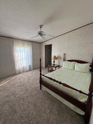 Une chambre à coucher avec un lit à baldaquin, un ventilateur de plafond, une table de chevet et une lampe.