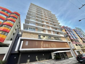 Un immeuble résidentiel à plusieurs étages, doté d’une architecture moderne, de balcons et d’une entrée de garage.