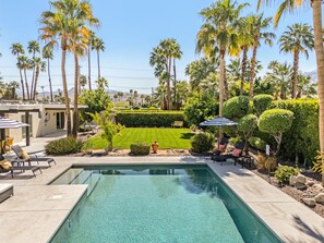 A swimming pool with a surrounding patio area, lounge chairs, and a well-manicured lawn. - Palm Springs Oasis | Private Pool, Spa & Game Room (Palm Springs)
