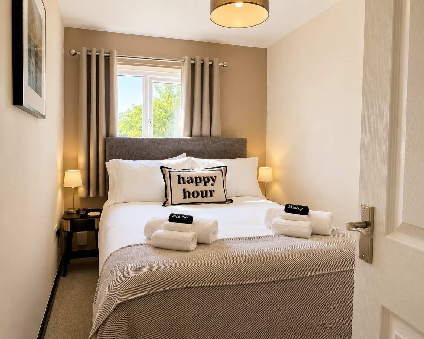 Une chambre d’hôtel avec un lit, deux lampes de chevet, une fenêtre avec des rideaux et une porte.