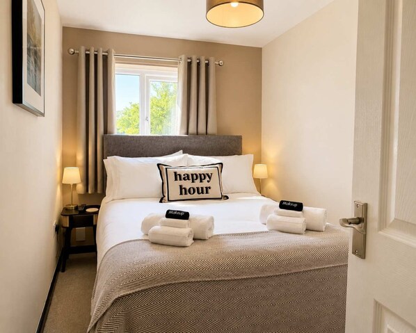 Une chambre d’hôtel avec un lit, deux lampes de chevet, une fenêtre avec des rideaux et une porte.