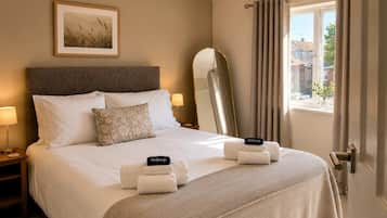 Une chambre d’hôtel avec un lit, une table de chevet, une lampe, un miroir et une fenêtre avec des rideaux.