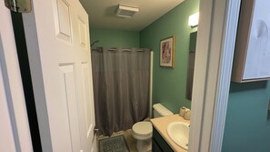 Un baño con inodoro, lavamanos y cortina de ducha.