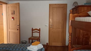 Una habitación con dos camas, una silla de madera y una litera.