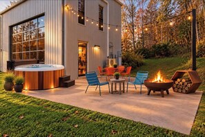 An outdoor patio with a hot tub, chairs, a fire pit, and a deck area. - The Looking Glass Modern Vermont Retreat with Private Hot Tub (Barnard)