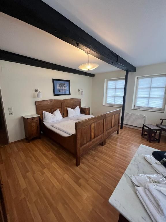 Ein Schlafzimmer mit einem hölzernen Bett, Nachttischen, einem Beistelltisch, einem Fenster und einer Heizung.