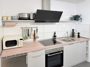 Une cuisine moderne équipée d’un four à micro-ondes, d’un four et d’un évier intégrés.