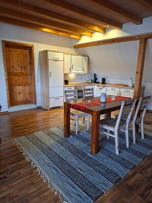 Uma cozinha com armários de madeira, uma mesa de jantar com cadeiras e um tapete no chão.