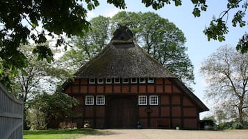 Een traditioneel gebouw met rieten dak, een grote houten deur en een bakstenen gevel.