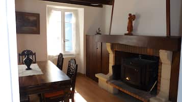 A dining area with a wooden table, chairs, a vase, and a fireplace.