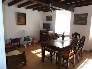 Een eetgedeelte met een houten tafel en stoelen, een televisie en kunstwerken aan de muren.